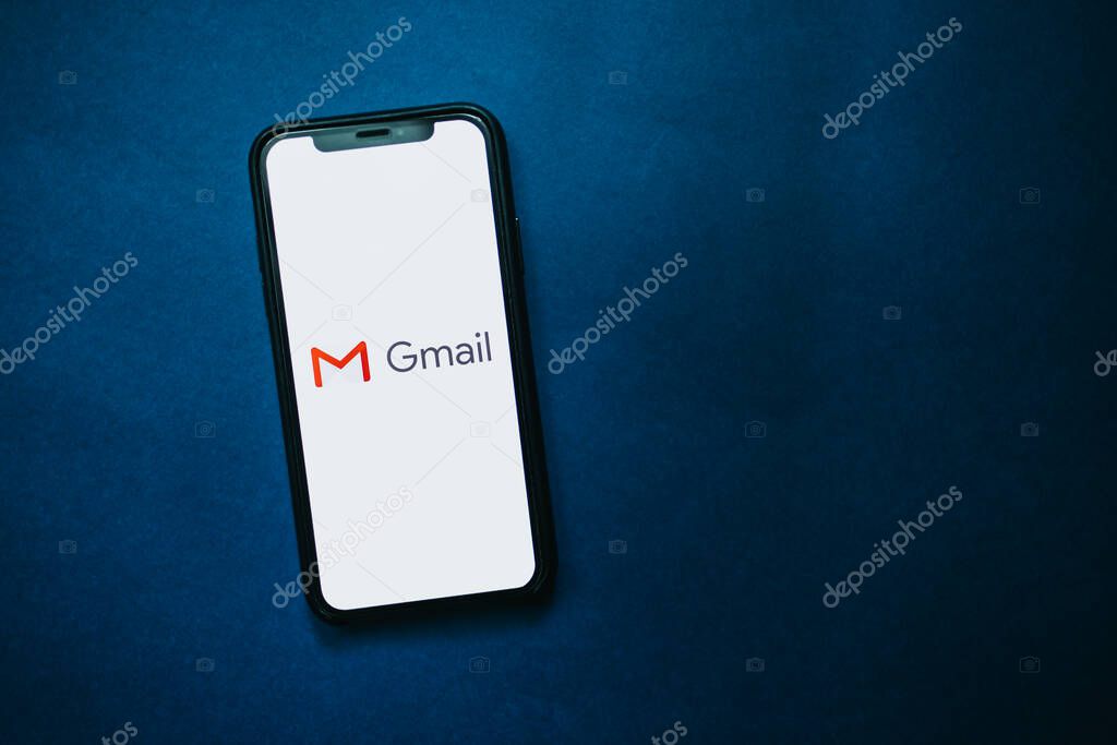 IPhone with Gmail app logo on the screen. blue background. High quality photo