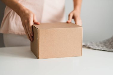 Elinde karton bir kutu tutan kadın, elinde bir paket..