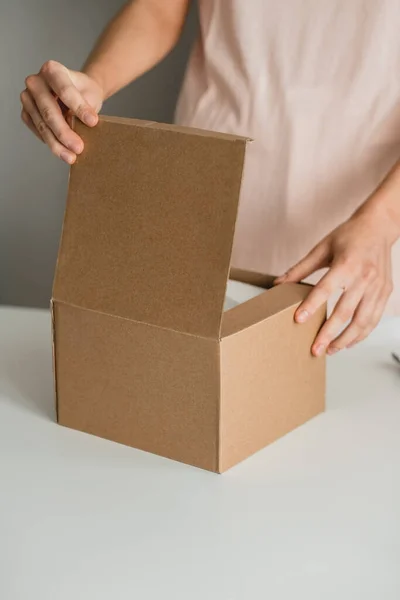 Woman opens a cardboard box. — Stock Photo, Image