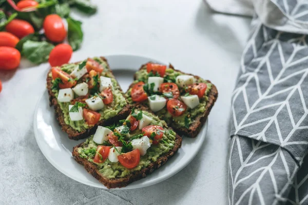 Bruschetta toast with guacamole and tomatoes.