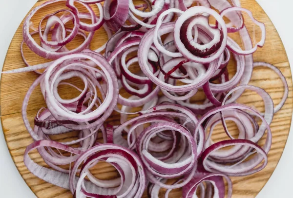 Red onion rings on a wooden board isolated on a white background.