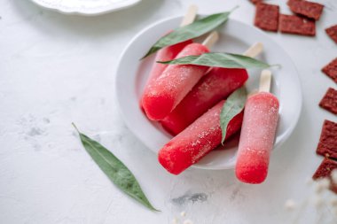 Beyaz bir tabakta pembe meyveli buzlu şerbet. Dondurma çubuğu. Yüksek kalite fotoğraf