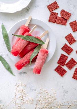 Beyaz bir tabakta pembe meyveli buzlu şerbet. Dondurma çubuğu. Yüksek kalite fotoğraf