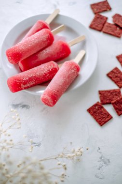 Beyaz bir tabakta pembe meyveli buzlu şerbet. Dondurma çubuğu. Yüksek kalite fotoğraf