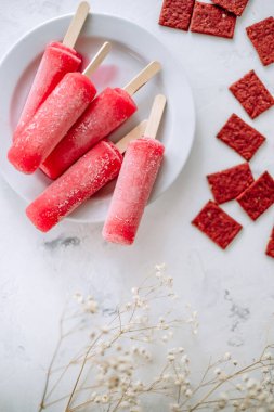 Beyaz bir tabakta pembe meyveli buzlu şerbet. Dondurma çubuğu. Yüksek kalite fotoğraf