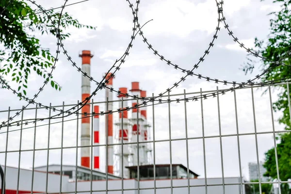 Industrial factory pipe and fence with barbed wire.