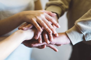 Yakın plan. Bir grup genç, birlik ve takım çalışmasının sembolü olarak ellerini birbirlerine sürerler. Yüksek kalite fotoğraf