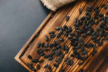 Tahta üzerinde siyah ayçiçeği tohumları ve siyah masa. Kapatın. Yüksek kalite fotoğraf