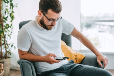 Kafkas sakallı genç adam, iş adamı, sandalyede oturuyor ve akıllı telefon kullanıyor. Yüksek kalite fotoğraf