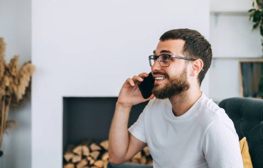 Kafkas sakallı genç adam, iş adamı, sandalyede oturuyor ve cep telefonuyla konuşuyor. Yüksek kalite fotoğraf
