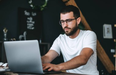 Beyaz sakallı genç adam evde çalışıyor, serbest çalışıyor, dizüstü bilgisayar kullanıyor. Yüksek kalite fotoğraf