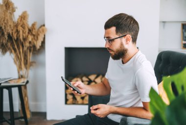 Kafkas sakallı genç adam, iş adamı, sandalyede oturuyor ve akıllı telefon kullanıyor. Yüksek kalite fotoğraf