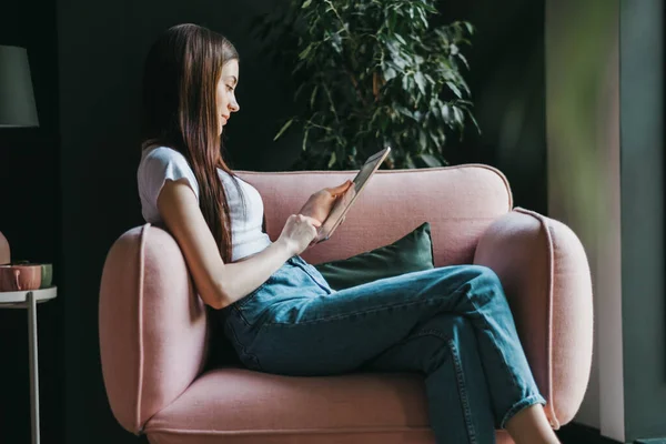 Mujer Caucásica Joven Sentada Sofá Rosa Usando Una Tableta Escribiendo — Foto de Stock