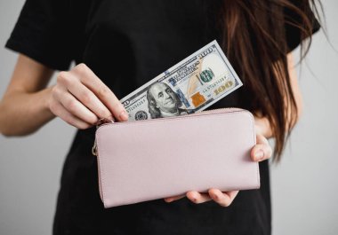 Genç bir kadın cüzdanından dolar banknotları çıkarır. Kapatın. Yüksek kalite fotoğraf