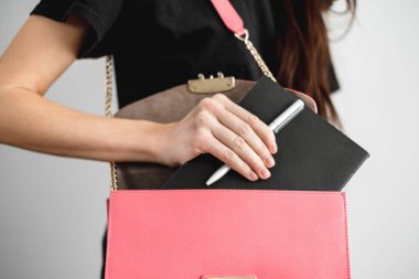 Genç, modaya uygun bir kadın not almak için çantasından bir defter ve kalem alır. Yüksek kalite fotoğraf