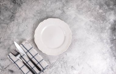 Gri arka planda çatal bıçak takımı olan boş beyaz tabak. Model yap. Yüksek kalite fotoğraf