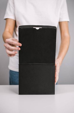 Kadın siyah bir karton kutuyu açıyor, paket beyaz bir masada. Teslimat konsepti. Yüksek kalite fotoğraf