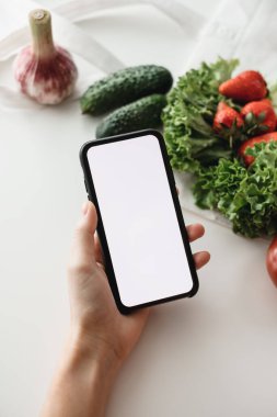 Akıllı telefonu beyaz ekranla tut, makara yap. Çevrimiçi gıda pazarı konsepti. Yüksek kalite fotoğraf