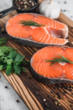 Tahta bir tahtanın üzerinde baharat ve otlarla birlikte taze somon balığı biftekleri. Yüksek kalite fotoğraf
