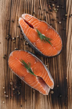 Tahta bir tahtanın üzerinde baharat ve otlarla birlikte taze somon balığı biftekleri. Yüksek kalite fotoğraf