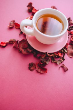 Pembe arka planda çay ve kurumuş taç yaprakları. Üst görünüm, boşluğu kopyala. Yüksek kalite fotoğraf