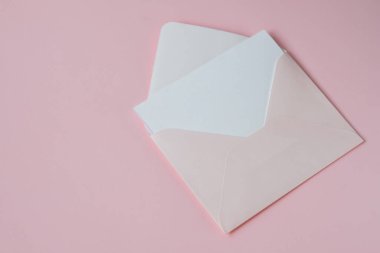 Pastel pembe arka planda izole edilmiş beyaz, boş kağıtlı pembe bir zarf. Model yap. Yüksek kalite fotoğraf