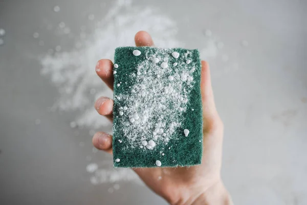 Green sponge with a cleaning powder in hand, closeup. High quality photo