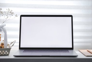 Güneşli bir günde penceresinde beyaz bir ekran ve bir not defteri olan bir laptop. İşyeri evi, modellik. Yüksek kalite fotoğraf