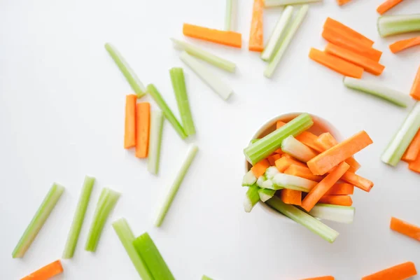 Sliced carrots and celery in a white bowl, healthy food background. High quality photo