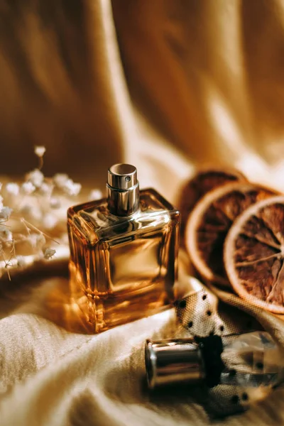 Butelka Perfum Złotym Satynowym Materiale Suszonymi Białymi Kwiatami Plasterkami Pomarańczy — Zdjęcie stockowe