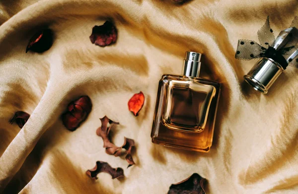 Butelka Perfum Złotym Satynowym Materiale Suszonymi Płatkami Kwiatów Zbliżenie Ciepłe — Zdjęcie stockowe
