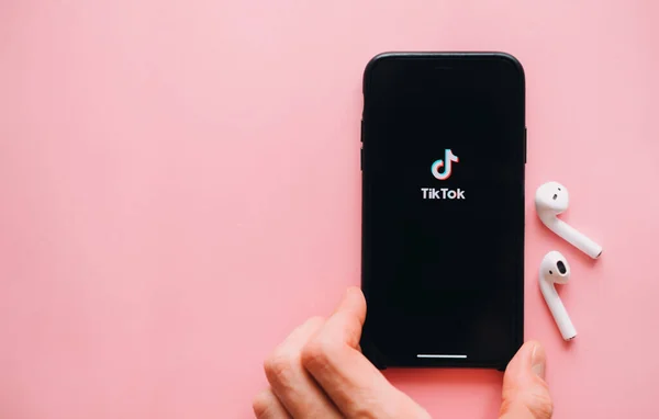 手持带有Tiktok应用标识的Iphone屏幕上的粉色背景 高质量的照片 — 图库照片