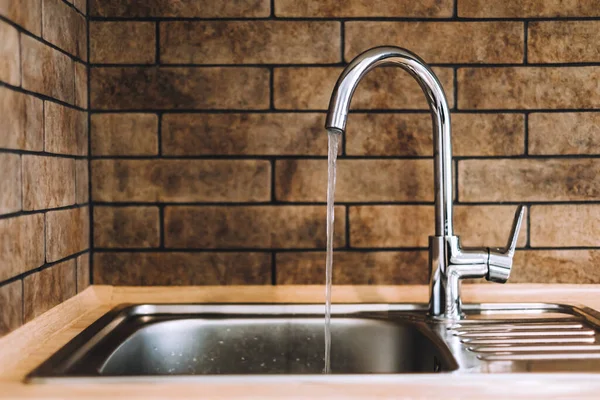 A running tap with the water running in the kitchen. The tap lets the water run, nobody. High quality photo