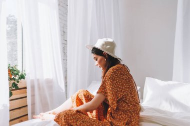 Güneşli bir sabahta beyaz şapkalı güzel bir kadın pencerenin yanında oturuyor. Dinlenme zamanı. Yüksek kalite fotoğraf