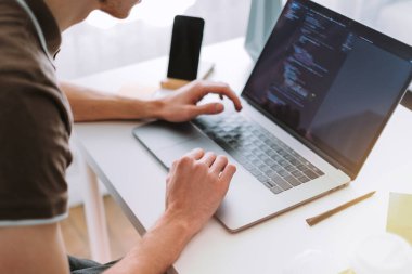 Genç adam mobil geliştirici, programcı merkez ofisteki bir dizüstü bilgisayara program kodu yazıyor. Yüksek kalite fotoğraf
