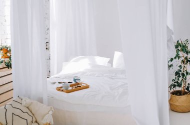 Yatak odasının içinde yumuşak yastıkları ve yeşil bitkileri olan rahat bir yatak. Yüksek kalite fotoğraf