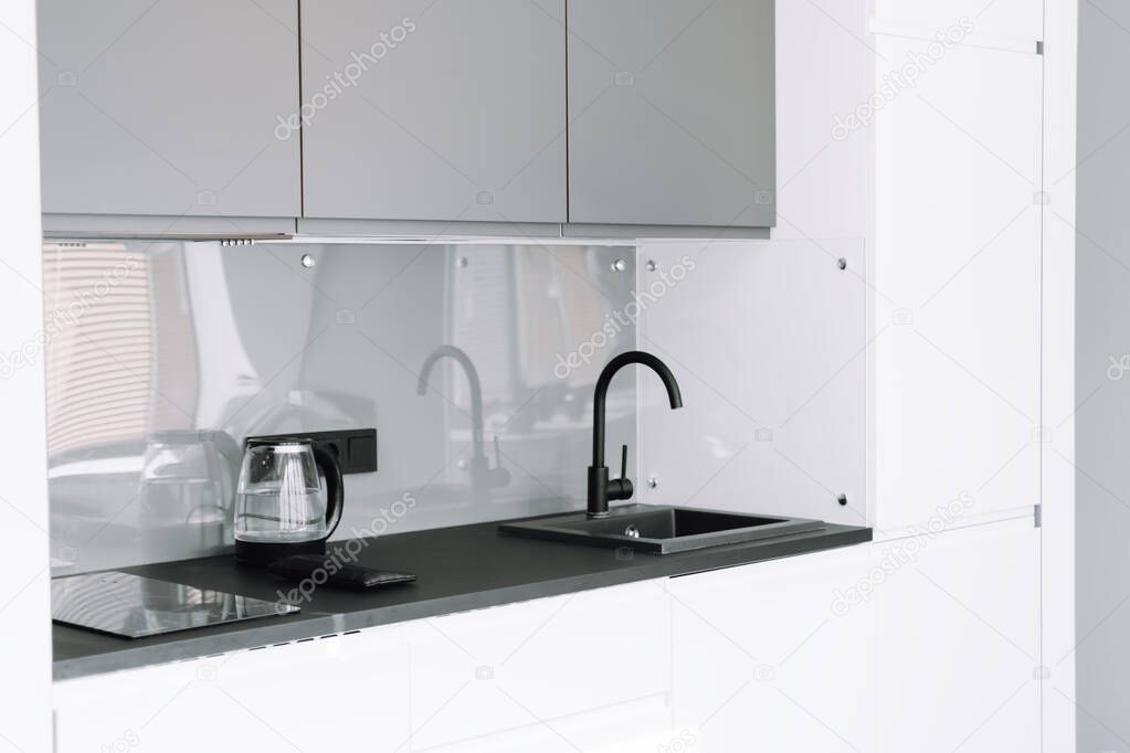 Interior of modern luxury grey and white wooden kitchen with black faucet and table. High quality photo