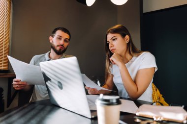 Genç bir çift dizüstü bilgisayarla oturma odasındaki banka hesaplarına bakarak finansman sağlıyor. Kadın ve erkek birlikte belgelere bakar. Bütçe harcamaları planlanıyor. Yüksek kalite fotoğraf