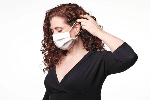 Kızıl saçlı kadın koronavirüs için koruyucu maske takıyor.