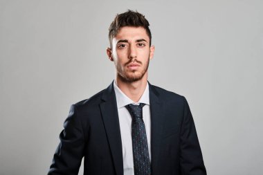 Koyu mavi bir takım elbise giyen genç adam portresi ve kameraya bakan kırmızı ve açık mavi noktalı koyu mavi bir kravat.