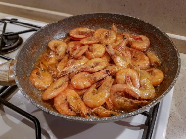 Yağı bir tavada bir gaz sobası üzerinde başlı dev portakal karides kızarmış