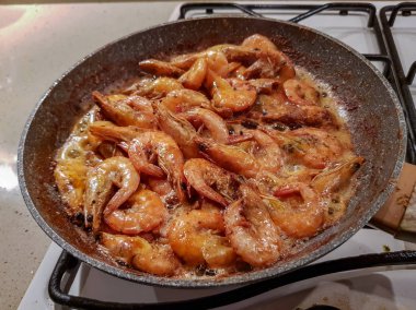 Yağı bir tavada bir gaz sobası üzerinde başlı dev portakal karides kızarmış