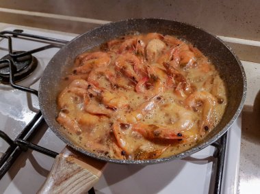 Yağı bir tavada bir gaz sobası üzerinde başlı dev portakal karides kızarmış