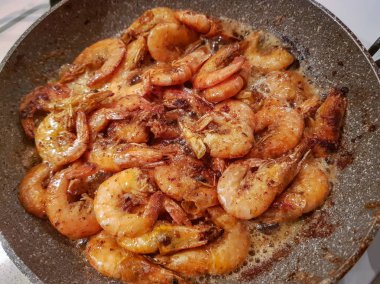 Yağı bir tavada bir gaz sobası üzerinde başlı dev portakal karides kızarmış