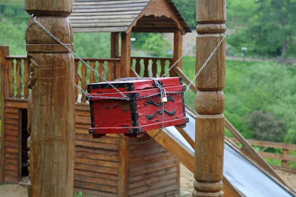 Red decorative chest of natural wood hanging on chains in the backyard