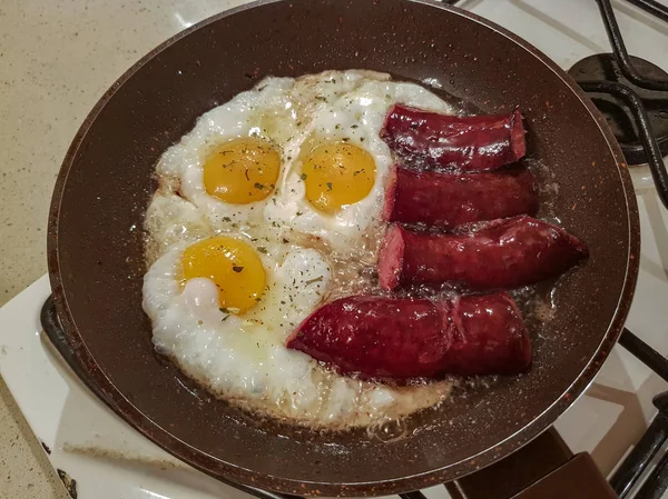 İştah açıcı Tütsülenmiş sosis ve yumurta kahvaltı için bir tavada yağda kızarmış