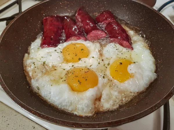 İştah açıcı Tütsülenmiş sosis ve yumurta kahvaltı için bir tavada yağda kızarmış