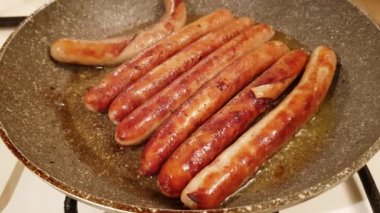 Büyük bir tavada kızarmış iştah açıcı kırmızı sulu sosis