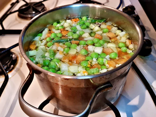 家庭のガスコンロで鍋で調理されるエンドウ豆 ニンジン セロリの野菜スープを沸騰 — ストック写真