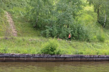 Kız nehir boyunca ormanda koşar.
